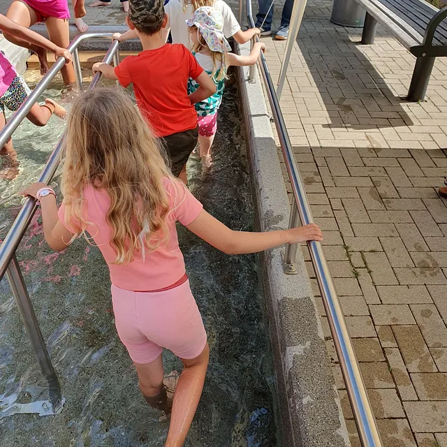 Kinder beim Wassertreten in einem Kneipp-Becken im Freien.