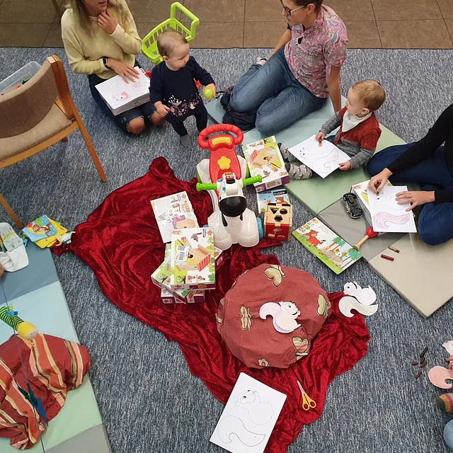 Eltern und Kleinkinder beim Malen und Spielen in einer Gemeindegruppe.