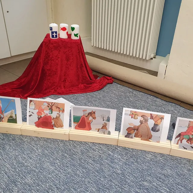 Sankt Martin Erzählkarten und drei verzierte Kerzen in einem Gemeinderaum.