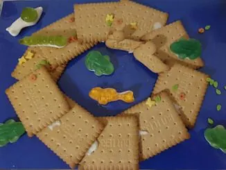 Butterkekse, die im Kreis auf blauem Grund angeordnet und mit Gummibärchen und Streuseln verziert sind.